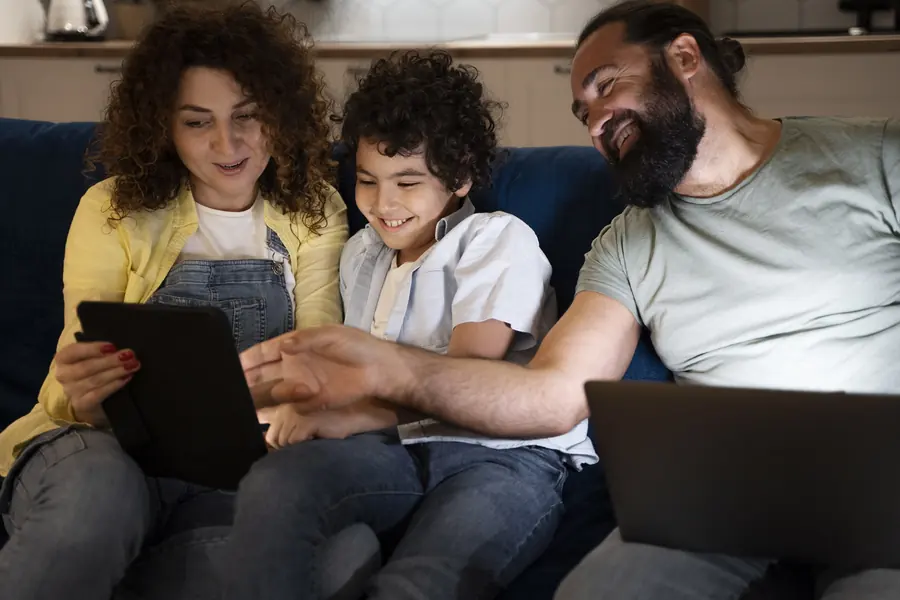 Família no sofá usando tablet e notebook conectados à internet